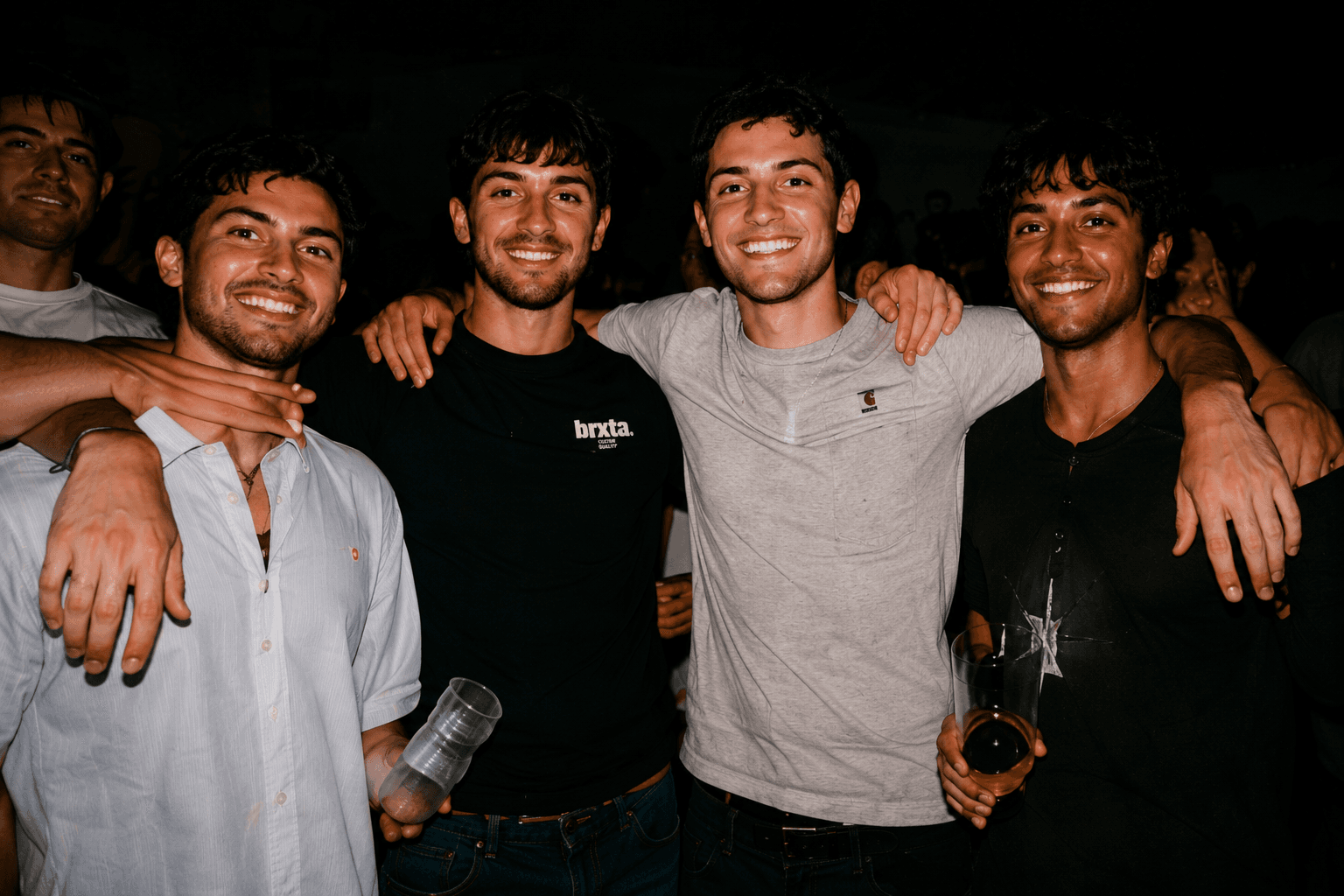Four friends standing together at a nighttime party