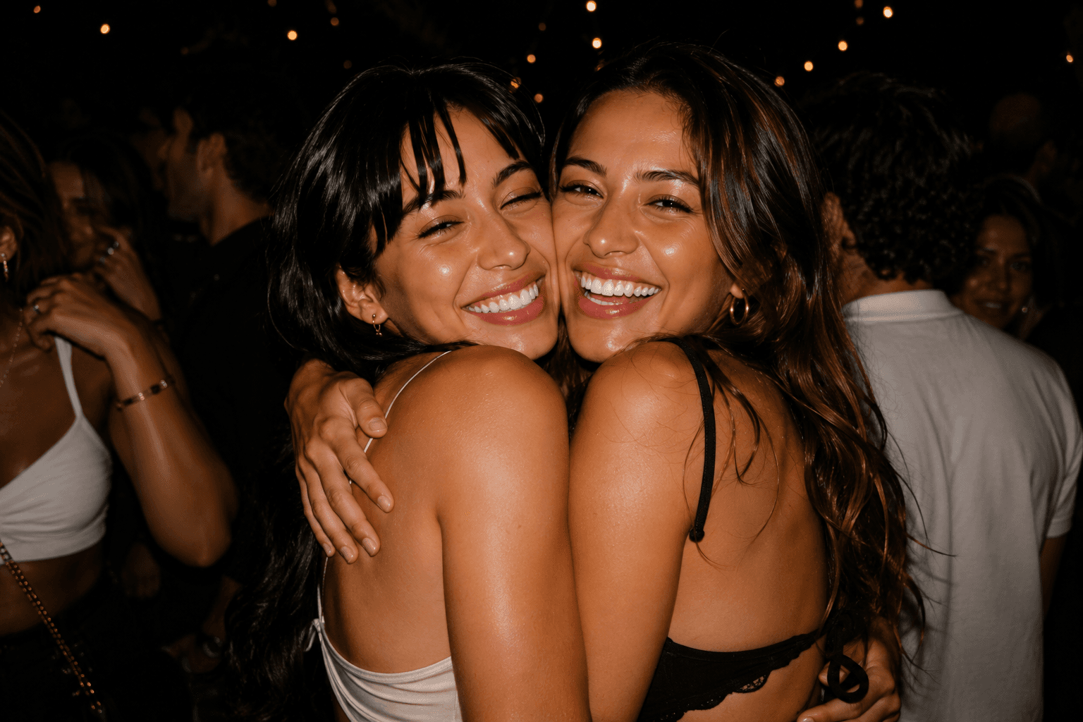 Two friends hugging and smiling at a nighttime party